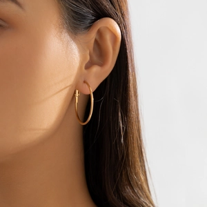 Close-up of model wearing large gold-tone hoop earrings with a polished metallic finish
