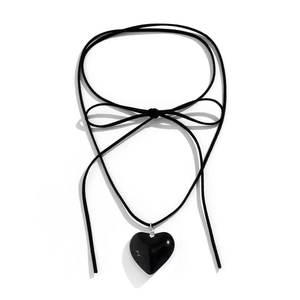 Detail of a large black heart pendant on a wax cord choker with a chic bow tie design
