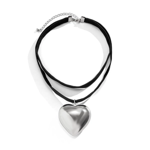 Detail view of a double-layered black velvet choker featuring a large silver heart pendant