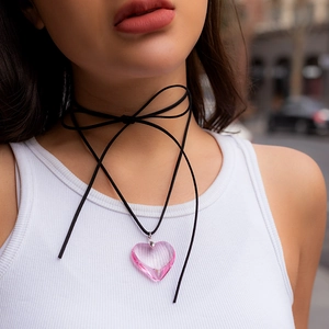 Close-up of a pink heart pendant on a long black adjustable string choker necklace