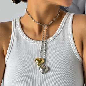 Detail of silver chain necklace with heart pendants in polished gold and silver finish