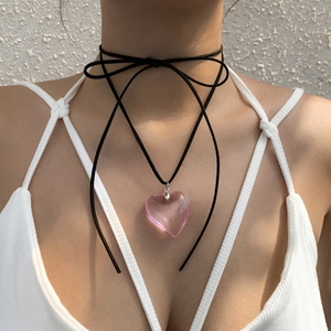 Detail of black ribbon choker necklace with pink acrylic heart pendant on a model
