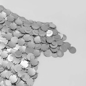 Dettaglio macro di paillettes argentate lucide e anelli di metallo del top a catena moda