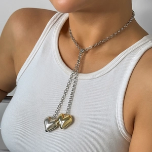 Detail of two-tone gold and silver heart pendants on a polished Y-shaped tassel necklace