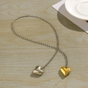 Detailed view of silver chain necklace with polished gold and silver heart-shaped pendants