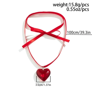 Detail of red ribbon bow choker featuring a translucent heart pendant on a white background