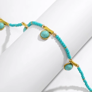 Detailansicht der türkisfarbenen Perlen und goldenen Röhren der Boho-Körperkette
