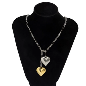 Detail of interlocking gold and silver heart pendants on a textured velvet chain necklace