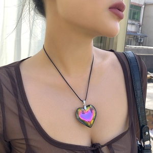 Close-up of iridescent heart pendant necklace featuring magenta and gold gradient effect