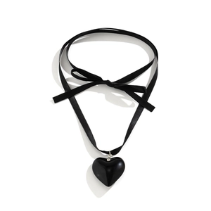 Detailed view of a black ribbon choker featuring a glossy heart pendant and elegant bow