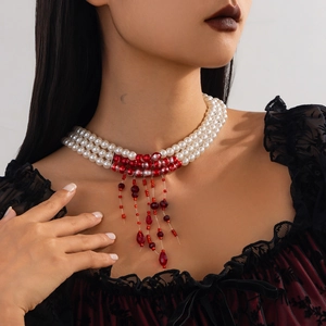 Macro detail of gothic triple-layer pearl choker necklace with red blood drop tassel
