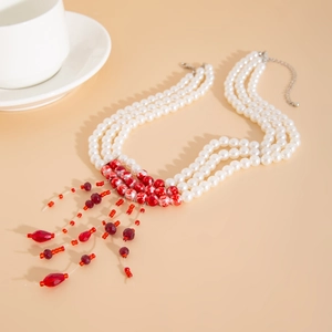 Macro shot of gothic white pearl choker with red bead tassels and silver adjust chain