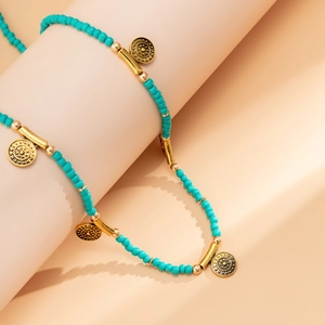 Detail einer Boho-Taillenkette mit türkisfarbenen Perlen und goldenen Münzanhängern