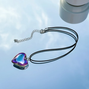Macro shot of gradient heart pendant with velvet chain on a reflective mirror background
