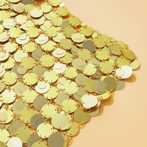 Dettaglio macro di paillettes metalliche dorate con finitura lucida a specchio e connettori