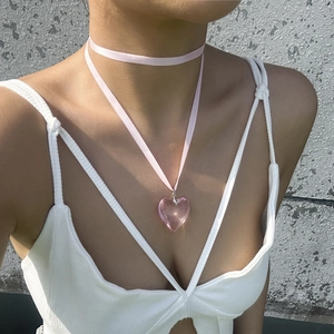 Close-up of a large pink resin heart pendant on a matching satin ribbon necklace