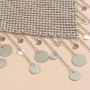 Macro shot of silver rhinestone mesh with tassel chains and polished sequin drops