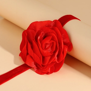 Detail van rode fluwelen rozenchoker met delicate bloemblaadjes en bijpassend lint op steun