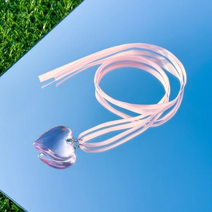 Pink transparent heart pendant necklace with adjustable silk ribbon on reflective sky