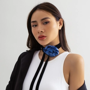 Detailopname van een koningsblauwe fluwelen rozenchoker met lang zwart lint bij een model