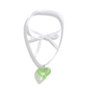 Close-up of green heart glass pendant on a white satin ribbon choker with bow detail