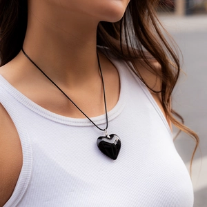 Detail view of a 3D black heart pendant necklace worn on a female model