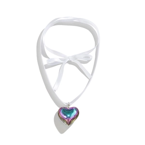 Detail of white silk ribbon bow with iridescent heart pendant featuring holographic colors