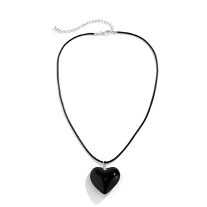 Macro detail of glossy black heart pendant on a minimalist black cord with silver clasp