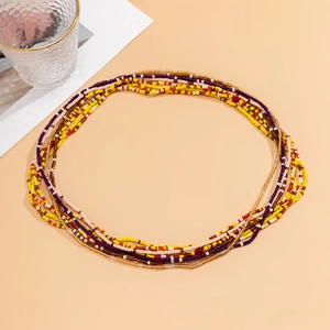Close-up of colorful layered beaded waist chain with boho style shell charm on warm background
