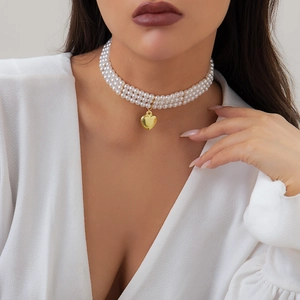 Détail d'un collier ras du cou à trois rangs de perles avec pendentif cœur doré poli