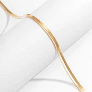 Macro detail of minimalist gold herringbone body chain with polished double layer metal texture