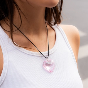 Close-up of translucent pink heart pendant on a thin black choker cord for women