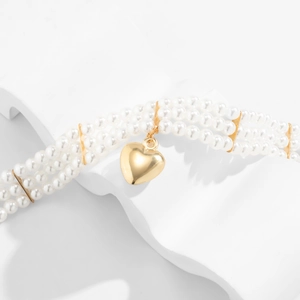 Détail d'un collier de perles à trois rangs avec pendentif cœur doré sur présentoir