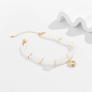 Détail du collier de perles à trois rangs avec pendentif cœur doré et chaîne réglable