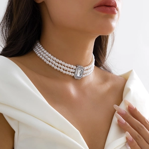 Détail d'un collier ras du cou élégant à trois rangs de perles et pendentif cristal