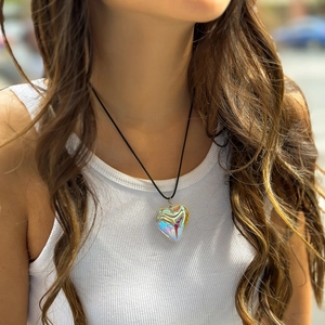 Close-up of iridescent heart pendant on a black velvet cord necklace worn by a model