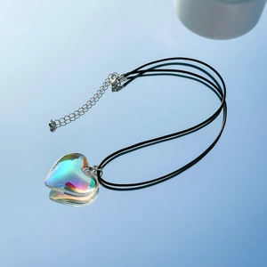 Detail of heart-shaped iridescent pendant on black cord necklace with silver clasp