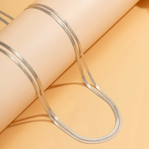 Detail of silver double-layered snake chain necklace over a cylindrical stand