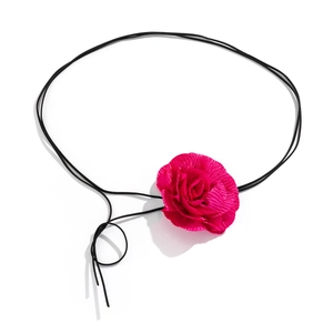 Detailweergave van handgemaakte choker met magenta stoffen roos en lange zwarte koord