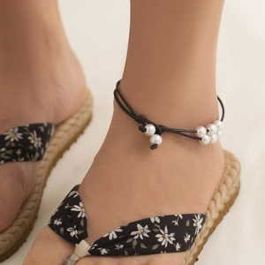 Detalle de la tobillera bohemia ajustable con perlas blancas y cordón negro trenzado