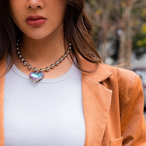 Iridescent heart pendant necklace with chunky silver bead chain on model in blazer