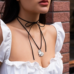 Detail of a black velvet choker with a hammered silver heart pendant tied in a bow