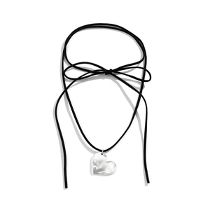 Detailed view of silver heart pendant with hammered texture on black suede cord necklace