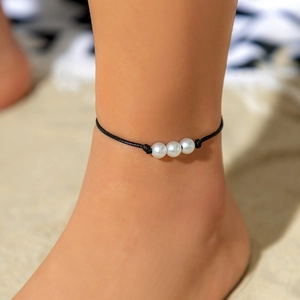 Detalle de la tobillera bohemia con tres perlas blancas sobre cordón trenzado negro