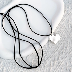 Close-up of a large silver heart pendant on a black adjustable wax cord necklace