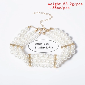 Détail du collier à trois rangs de perles blanches avec des séparateurs en métal doré ondulé