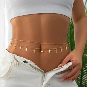 Detail of double-layer gold waist chain with dangling metal crosses on a woman's waist
