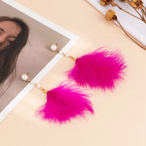 Detail of elegant magenta feather earrings with white pearls and gold metal accents