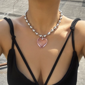Close-up of a pink resin heart pendant on a large silver bead chain necklace