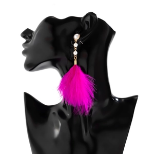 Detailed shot of long drop earrings with white pearls and vibrant pink feather tassels